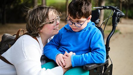 A mother and child using a wheelchair in the park.