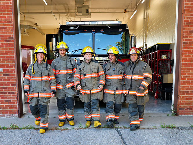 Clarington volunteer firefighters stand in front of a fire truck.
