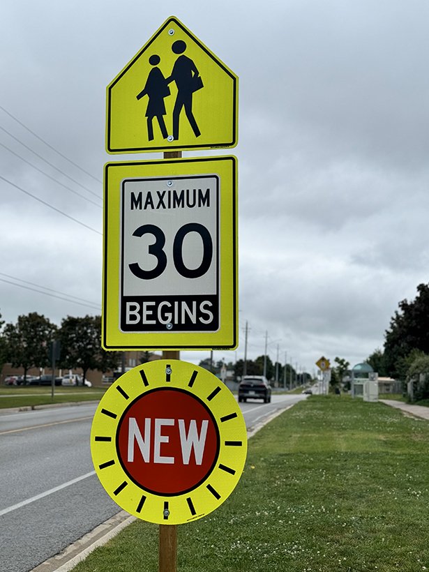 Image of a school zone sign with a new 30 km/hour sign below.