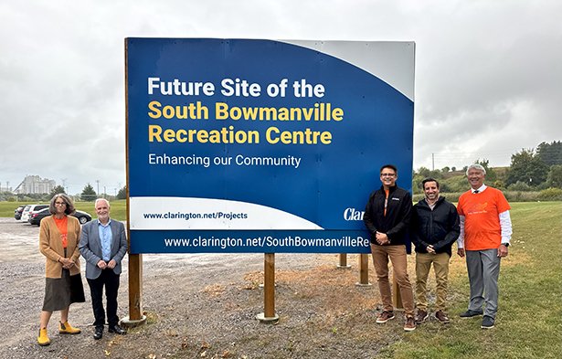 Members of Clarington Council at the future site of South Bowmanville Recreation Centre standing with a sign reading 'Future site of the South Bowmanville Recreation Centre. Enhancing our community.