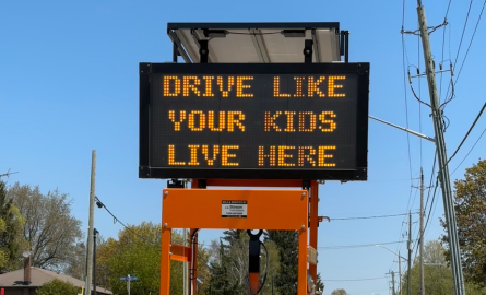 A digital sign with the message "Drive Like Your Kids Live Here"