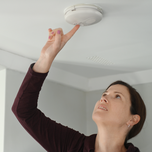 Woman testing a smoke alarm.